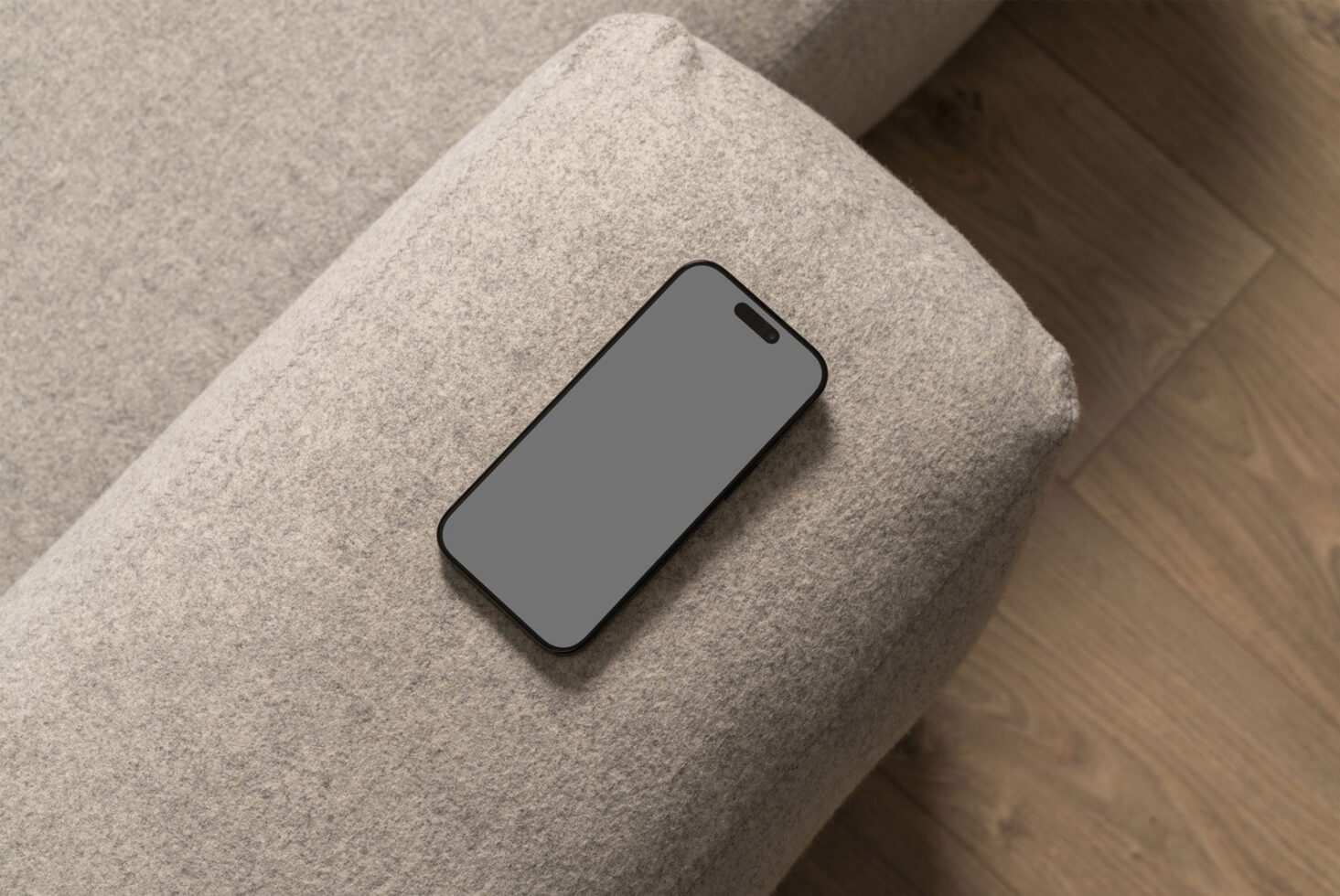 Smartphone mockup on a textured gray fabric sofa with wood floor background suitable for designers creating mobile app presentations and showcasing UI design.