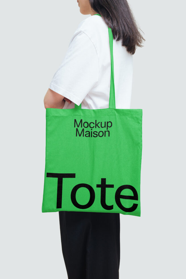 Green tote bag mockup held by a person in a white shirt, ideal for showcasing design templates. Perfect for designers looking for bag graphics.