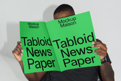 Mockup image of a person holding a large green tabloid newspaper with bold text ideal for design projects digital mockups and graphic templates for designers.