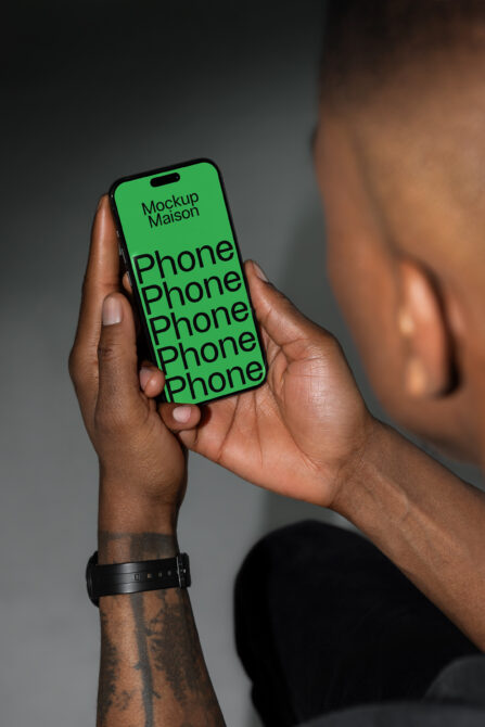 Phone mockup held by a person with a black watch showcasing bold green screen design. Ideal for app design presentations and device display templates.