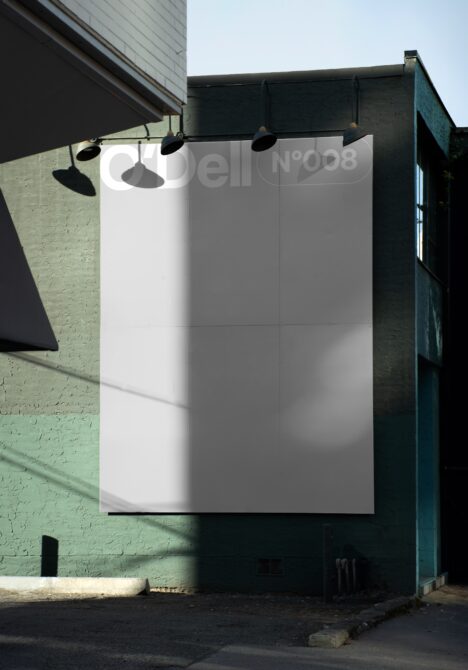 Urban wall billboard mockup in alley; sunlight casts shadows on green textured surface; ideal for showcasing advertisement designs; city street scene