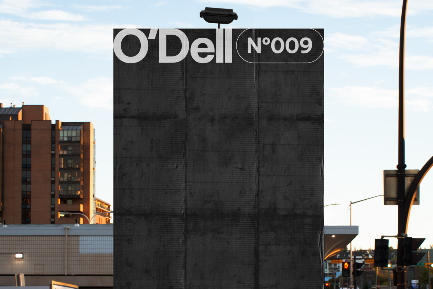 Urban billboard mockup featuring a large black surface with the text O'Dell No009 at dusk. Ideal for showcasing outdoor advertising designs.