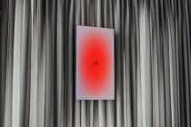 Digital display mockup showing red gradient with ply text on neutral curtain backdrop