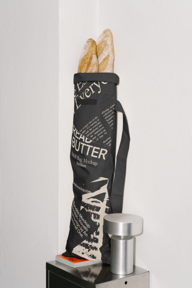 Mockup of a black bread bag with bold typography holding baguettes against a white wall. Ideal for designers seeking minimalist packaging designs.