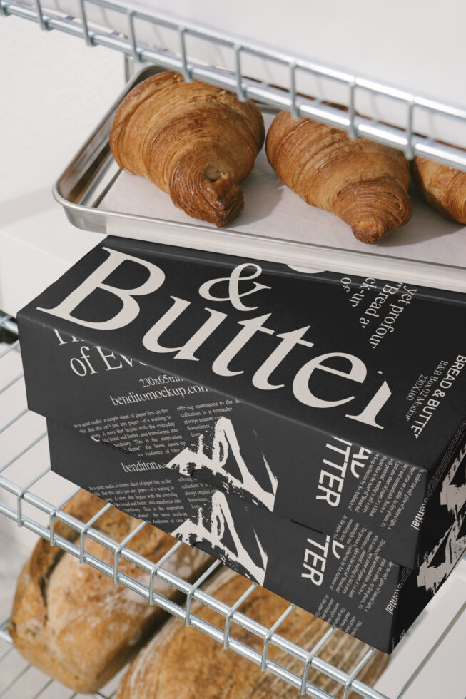 Bakery packaging mockup with black and white typography box beneath croissants on a tray. Ideal for designers looking for food branding templates.