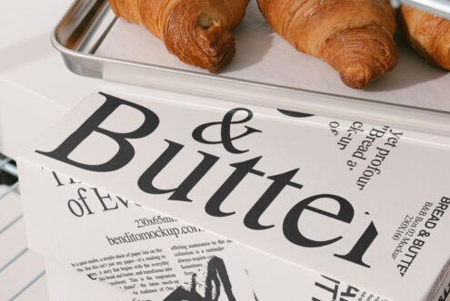 Mockup design featuring paper box with bold typography Bread and Butter next to croissants on a tray; perfect for packaging designers and branding projects.