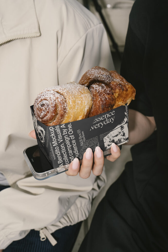 Pastry packaging mockup featuring assorted pastries inside a trendy, customizable box held by a hand. Ideal for food graphic design and branding.