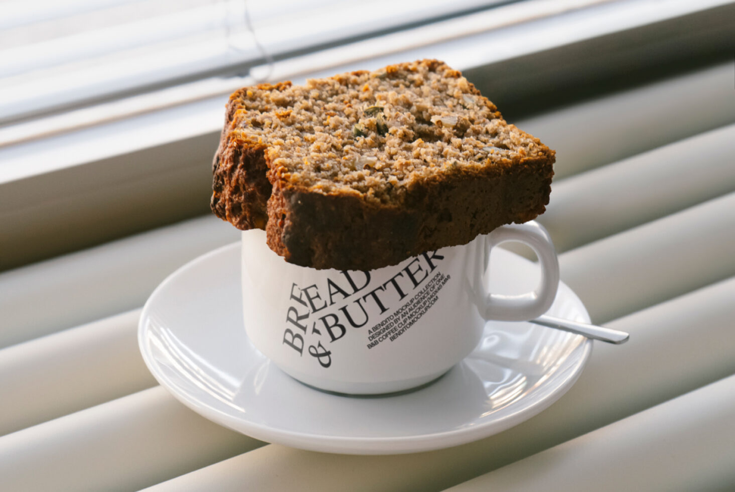 Slice of rustic bread on a cup labeled Bread and Butter sitting on a saucer. Ideal for food-themed graphic design, mockup, template for designers.