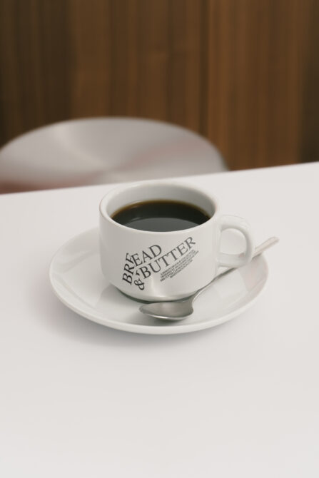 Coffee cup mockup with Bread and Butter branding on table background ideal for designers looking for realistic product presentation templates graphics.