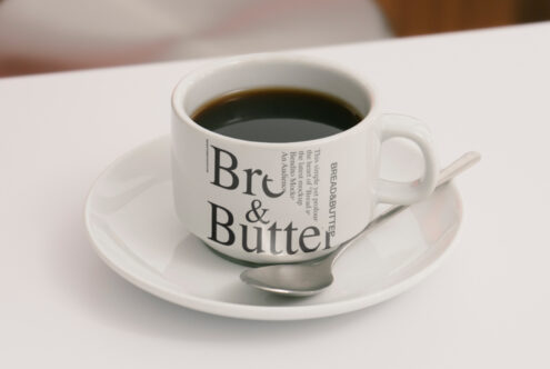 Coffee cup mockup on a saucer with spoon for designers. Features typography design. Perfect for showcasing branding, packaging, and font projects.