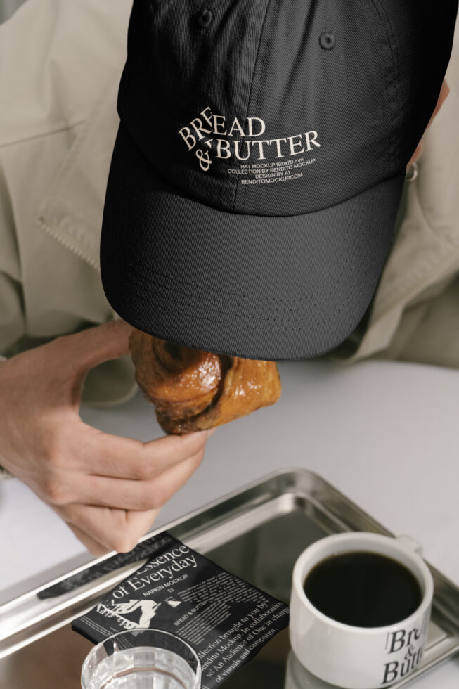 Man wearing Bread and Butter cap, eating pastry. Tea cup on table. Hat design mockup for fashion, branding. Ideal for template, mockup needs.