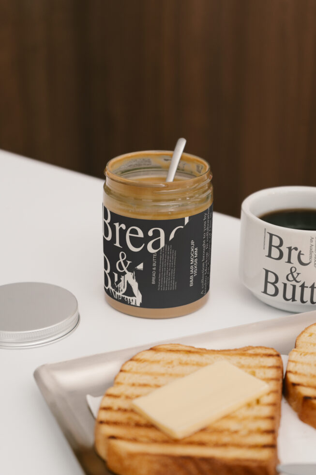 Editable jar mockup with bread and butter packaging, perfect for branding design. Includes toast and coffee cup, ideal for designers seeking realistic assets.