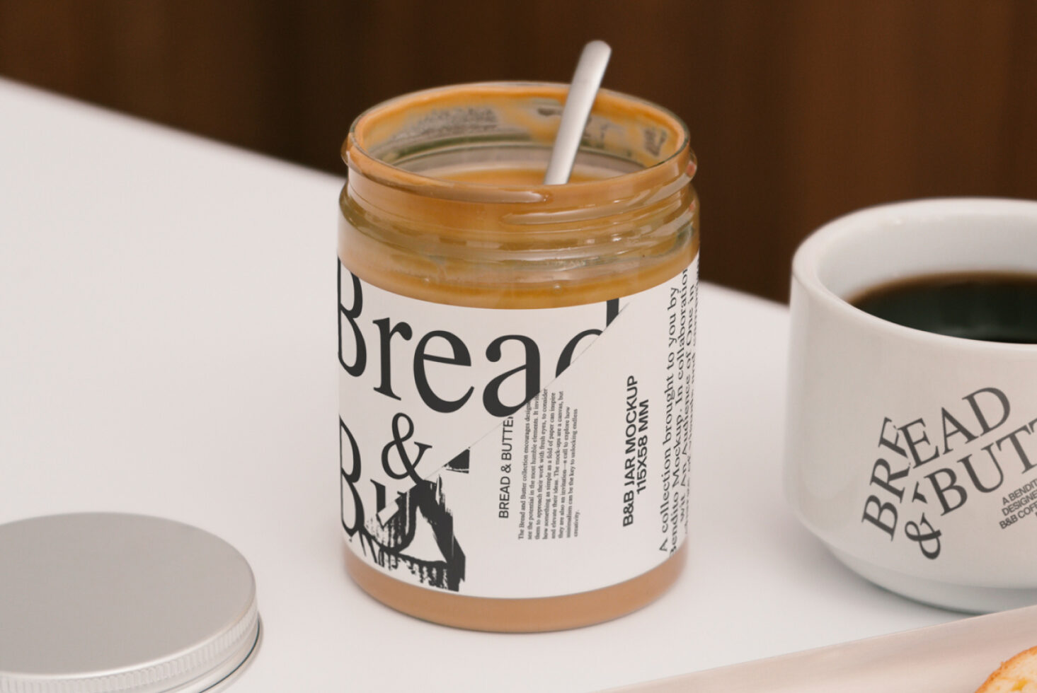 Jar mockup with peanut butter label design featuring typography. Includes coffee cup and jar lid. Ideal for showcasing product design templates for designers.