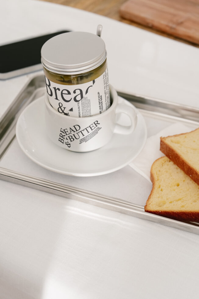 Styled jar and cup mockup on tray with sliced bread, perfect for showcasing branding designs. Ideal for designers seeking high-quality product mockups.