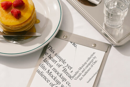 Flat lay of pancake breakfast with fork and knife on plate, next to paper and tray mockup. Ideal for food-themed designs, branding, and templates.