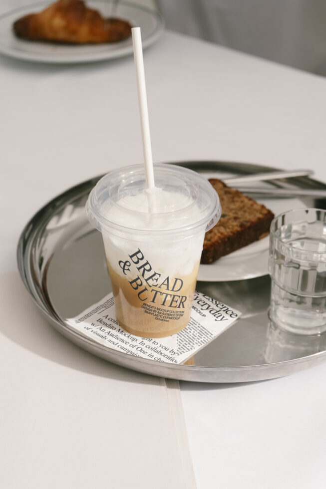 Coffee cup mockup on tray with brown bread and water glass, ideal for branding templates, packaging design, realistic presentation for designers.