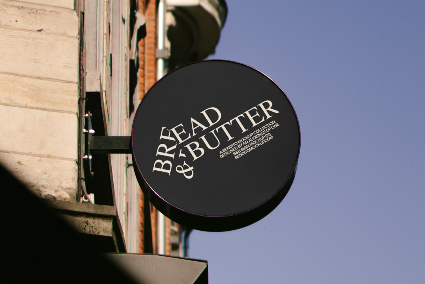 Round storefront sign mockup reading Bread and Butter on a building facade ideal for branding and design presentation. Keywords: mockup, branding, sign.