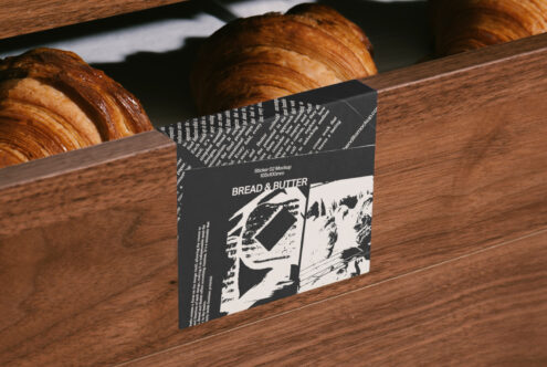 Sticker mockup displayed on rustic wooden surface with croissants; ideal for showcasing bakery branding; perfect for design templates and graphics.