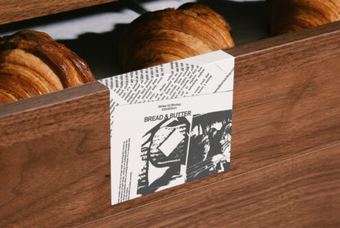 Wooden bread box with croissants and newspaper-themed sticker design mockup Bread and Butter ideal for designers seeking unique packaging graphics.