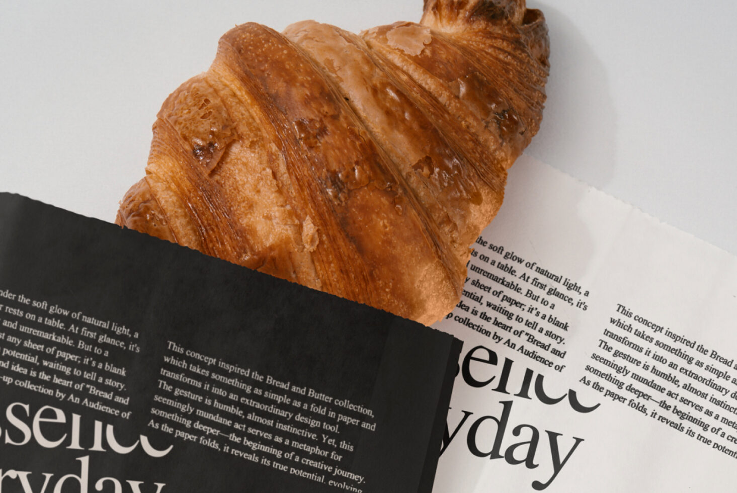 High-quality mockup featuring a fresh croissant atop stacked newspapers. Ideal for designers seeking realistic food styling and editorial graphics.