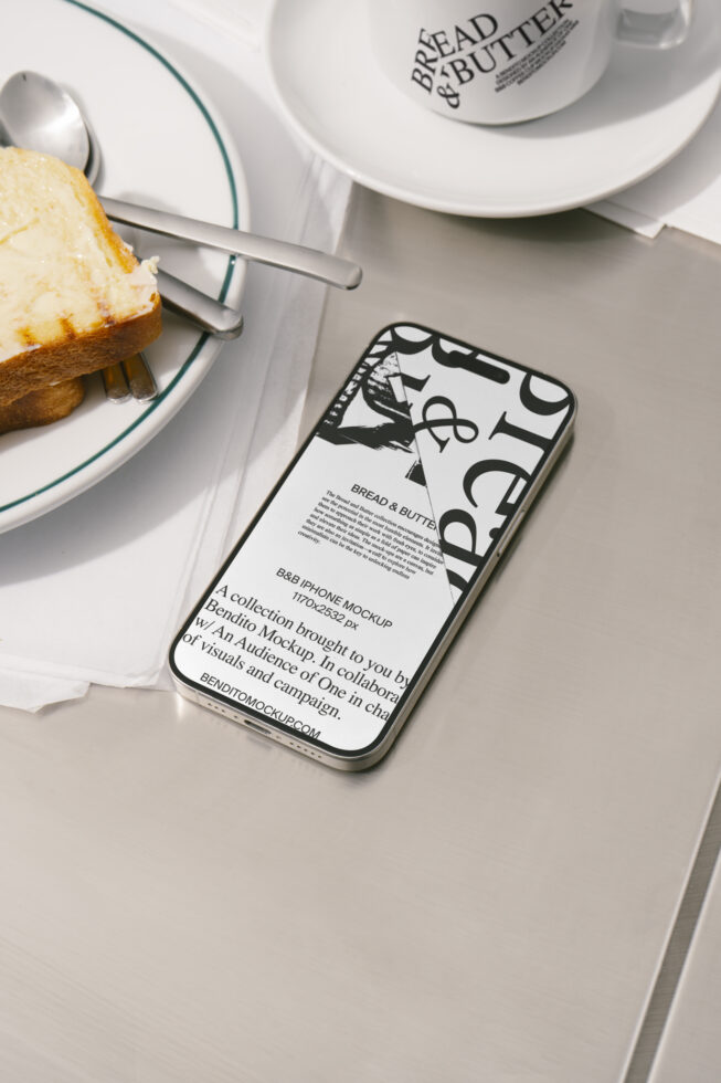 Phone mockup on a table with toast and coffee. Design features bold typography. Ideal for showcasing UI and UX designs. Great for creative presentations.