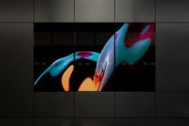 Colorful abstract liquid shapes in cyan, orange flowing across grid-based display wall