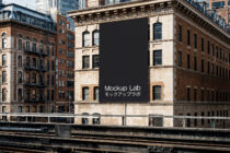 Black billboard mounted on historic building above train tracks