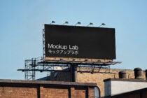 Blank rooftop billboard with lit base against clear sky
