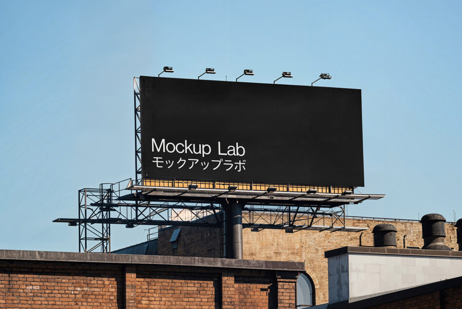 Blank rooftop billboard with lit base against clear sky