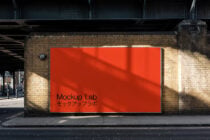 Wide red display panel on brick facade with black Mockup Lab typography