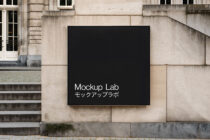 Black rectangular sign on beige stone wall with white text saying Mockup Lab