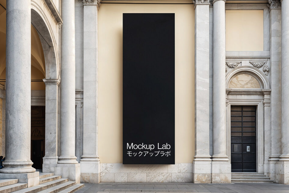 Black vertical banner mockup hung between ornate stone columns on classical building facade