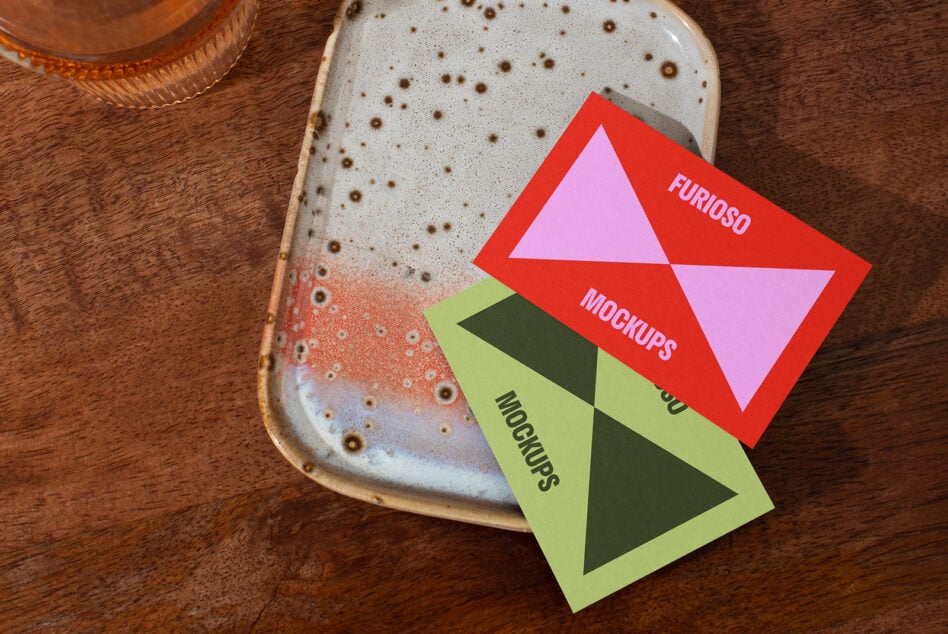 Two colorful mockup cards placed on a ceramic tray and wooden table. Design assets for creatives looking for vibrant presentation templates.