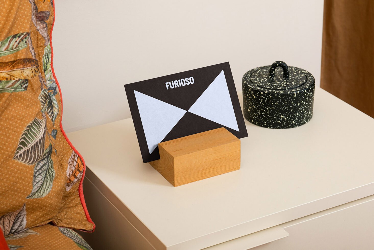 Mockup featuring a black and white card with geometric design on wooden stand, ideal for showcasing fonts or graphic projects for designers.
