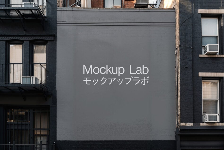 Gray building billboard mockup between urban brick structures with white Mockup Lab text