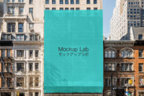 Bright turquoise construction banner covering NYC building facade with Mockup Lab text