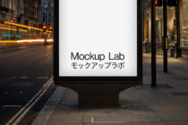 Street billboard mockup on downtown corner at evening with storefront glow