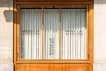 Classic wood storefront with three glass panels showing Mockup Lab text on both sides