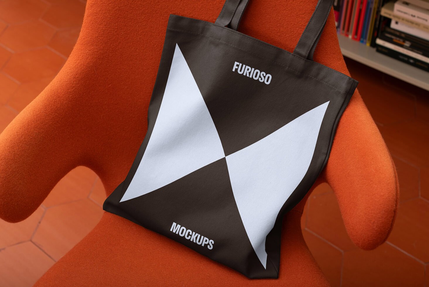 Tote bag mockup on orange chair showcasing abstract black and white geometric design. Ideal for branding presentations and product showcases for designers.