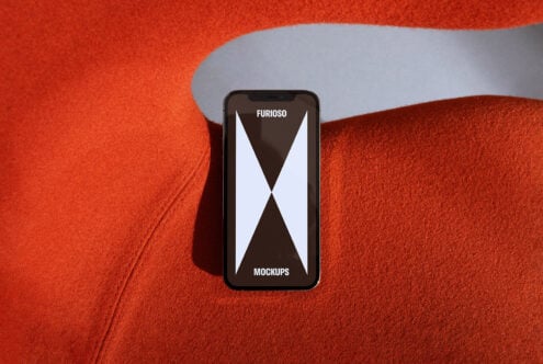 Smartphone mockup displayed on vibrant orange fabric background. Modern minimal design perfect for showcasing digital assets for graphic designers.