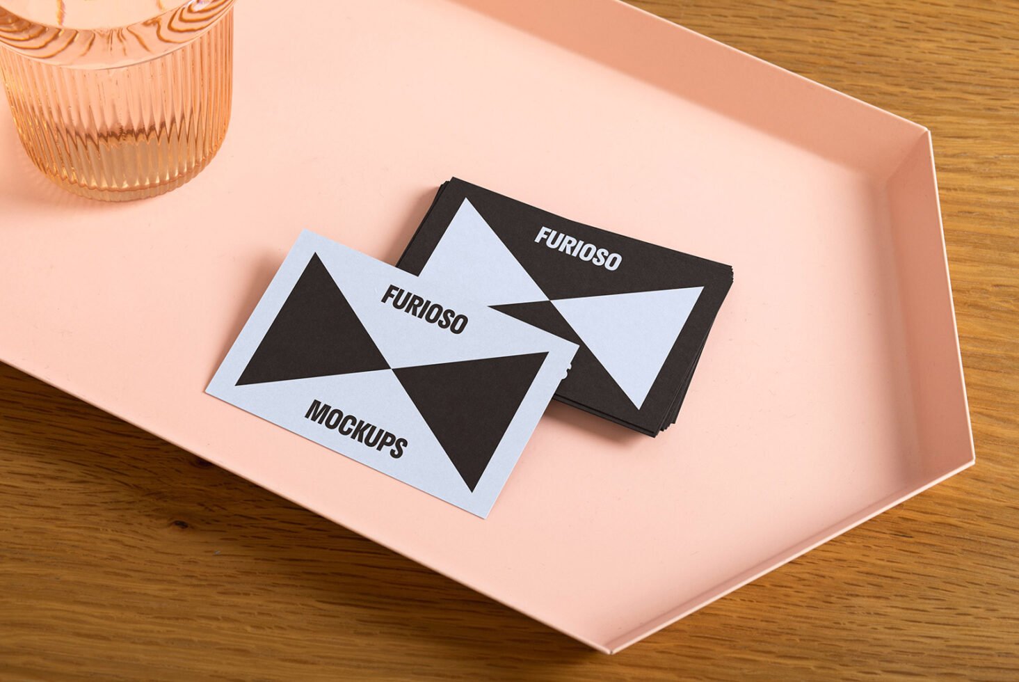 Business card mockup on a pink tray with a glass. Perfect for designers seeking stylish presentation templates for branding or stationery projects.