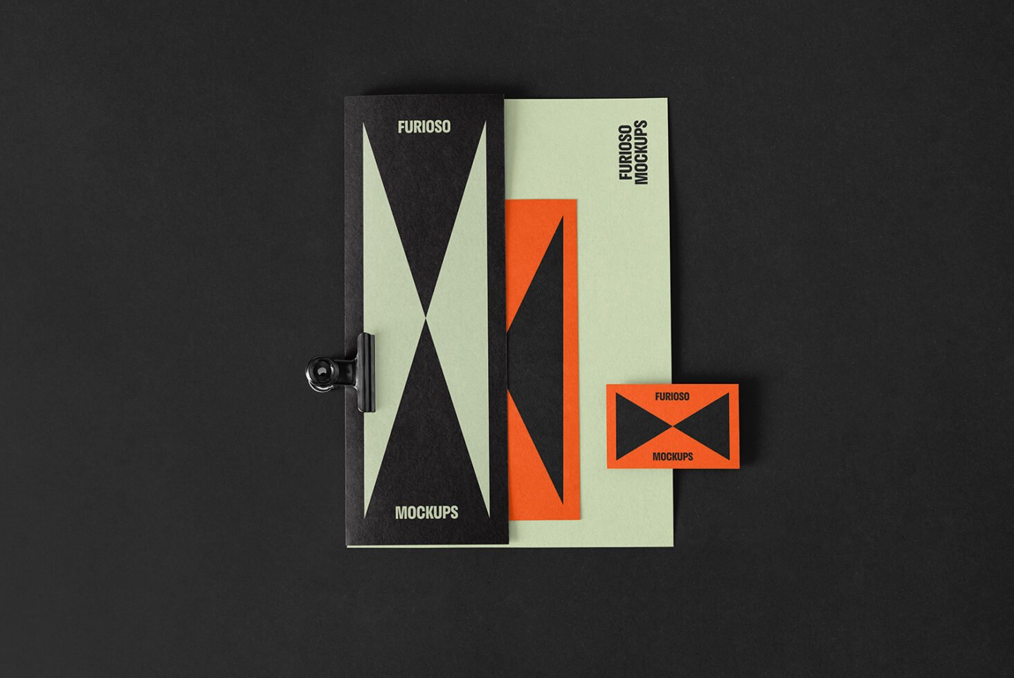 Top view of modern brochure design mockups featuring geometric patterns in black and orange on green paper laying on a black background suitable for designers