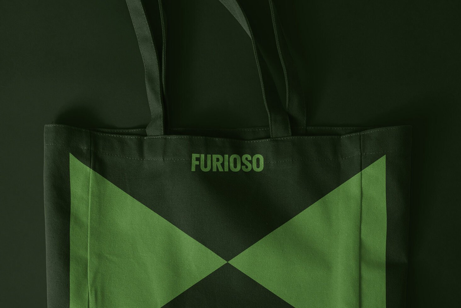 Dark green tote bag mockup with stylized text Furioso featuring bold geometric design. Ideal for branding and graphic design projects. High-quality asset.