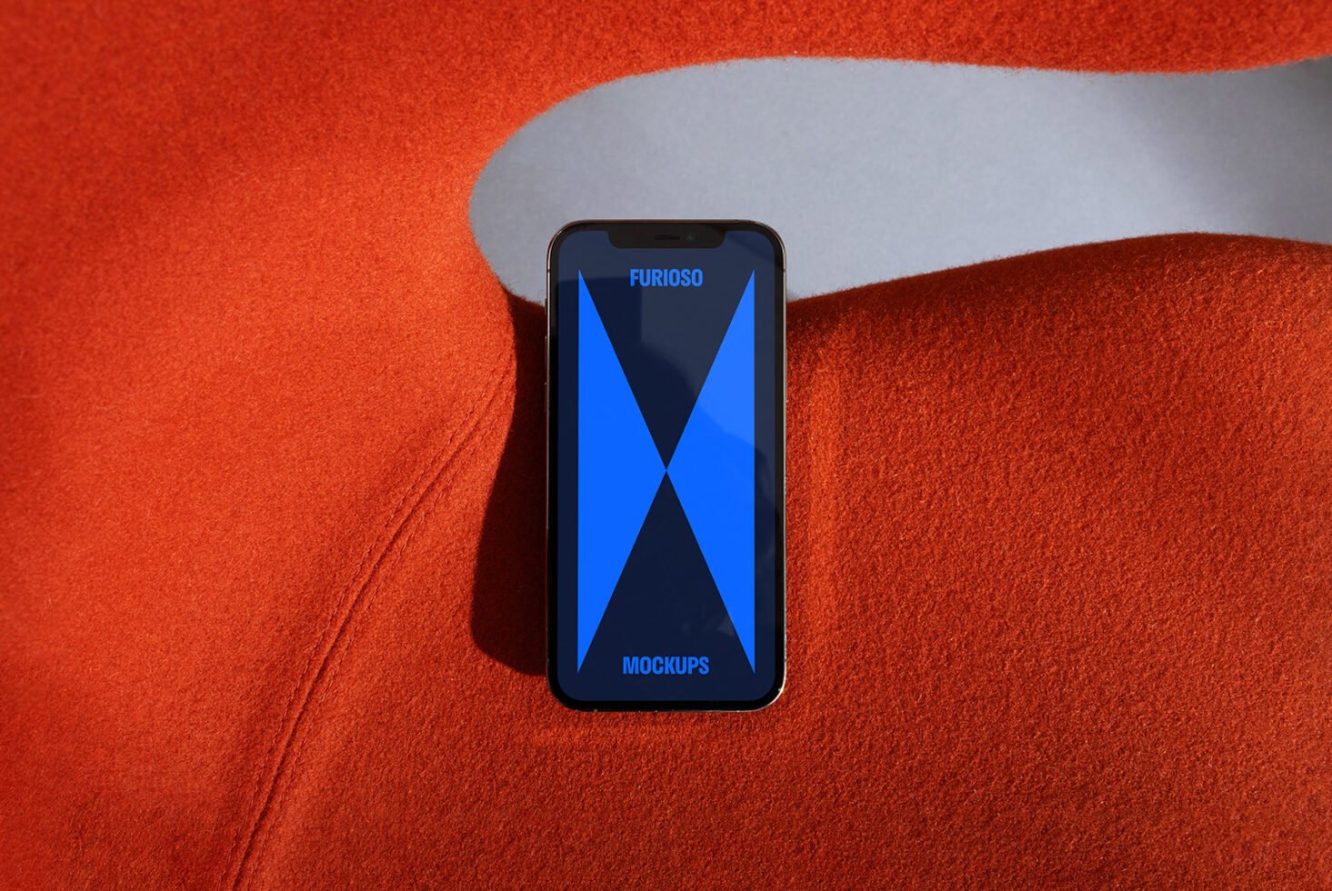 Smartphone mockup with blue geometric design on screen placed on vibrant orange fabric. Perfect for showcasing app designs. Ideal for designers.