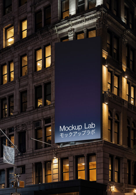 Dark vertical billboard on historic facade lit by warm window glow below