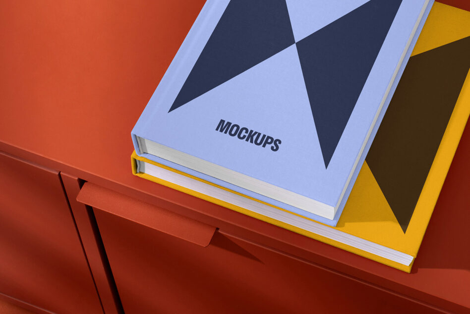 Colorful book mockups with geometric designs on red surface perfect for designers seeking high-quality assets for templates and creative projects.