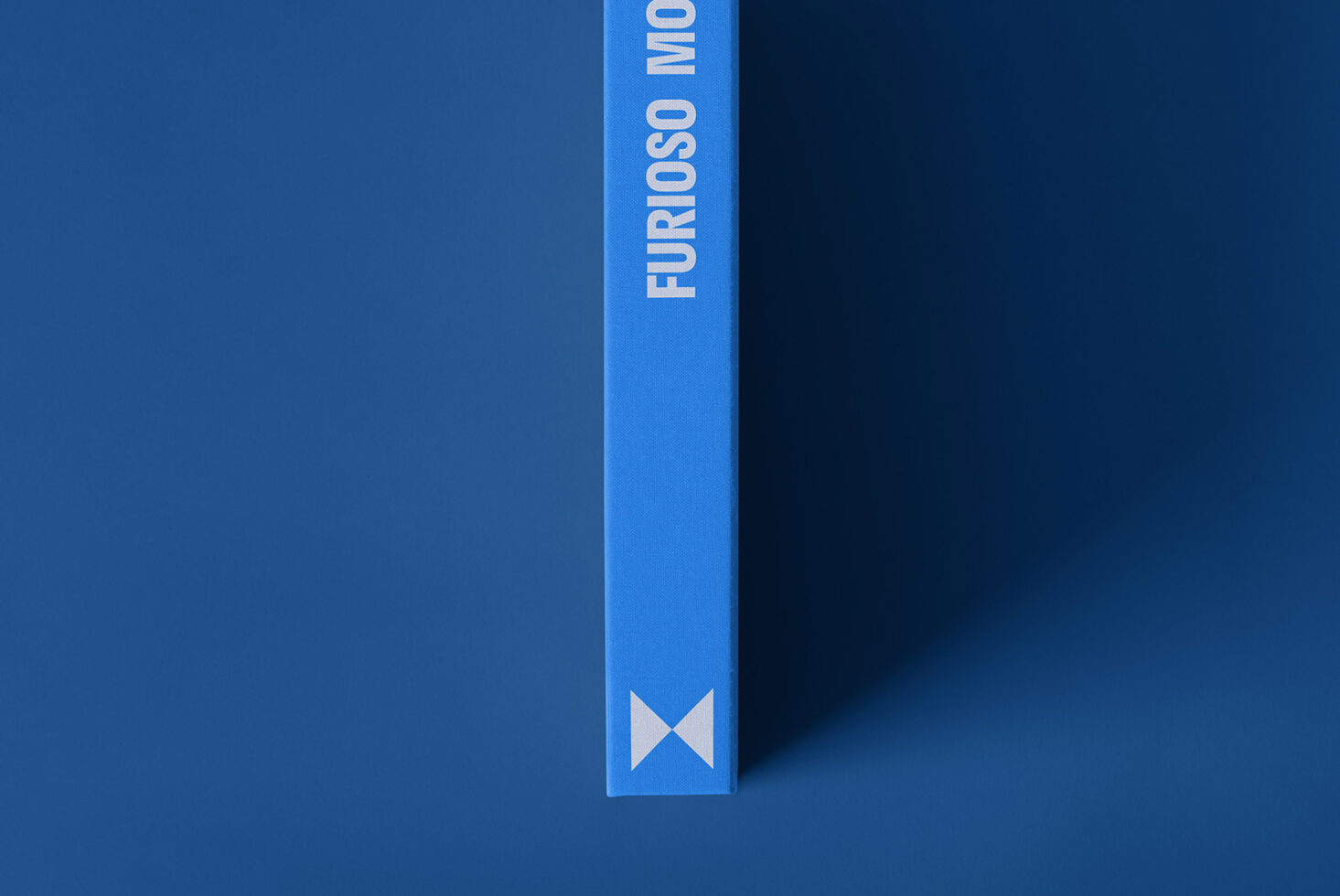 Blue hardcover book mockup with vertical text Furioso on spine for graphic design projects. Ideal for showcasing layouts and templates in a minimal style.