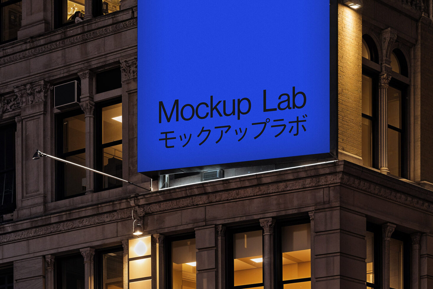 Urban building facade with large illuminated blue billboard reading Mockup Lab in English and Japanese. Night scene suitable for advertising mockups.
