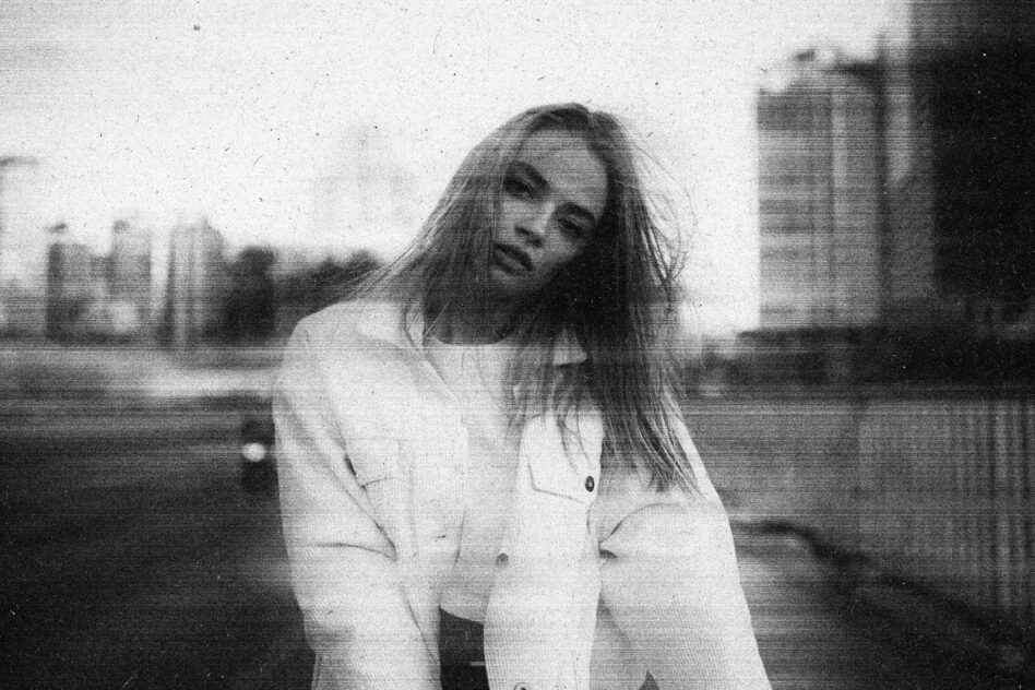 Black white portrait with grainy film texture, blurred cityscape behind subject