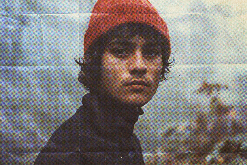 Portrait with halftone dot effect, person in red beanie against pixelated sky